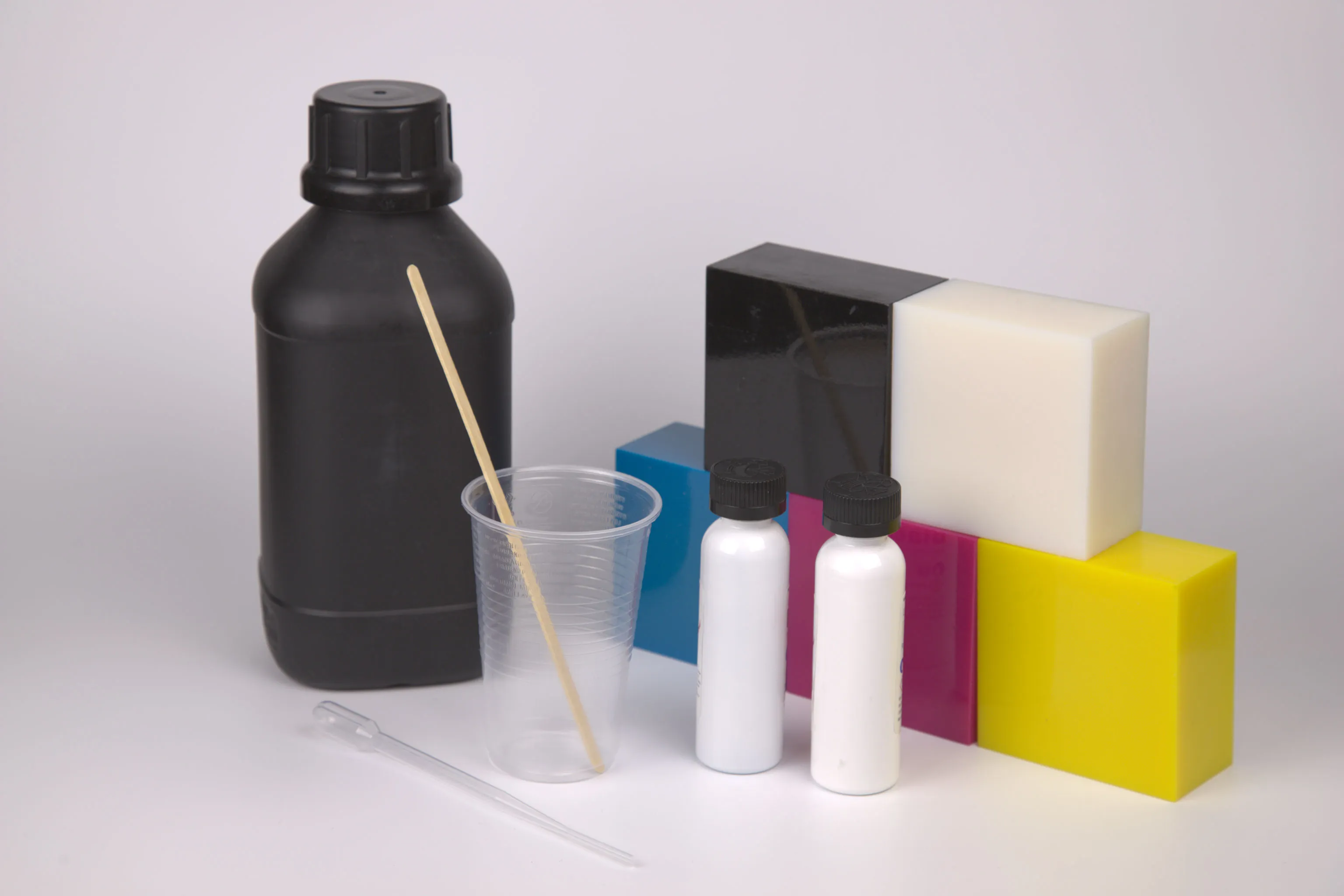 Cyan Magenta Yellow Black and White (CMYKW) resin blocks and pigment bottles for a clear resin.